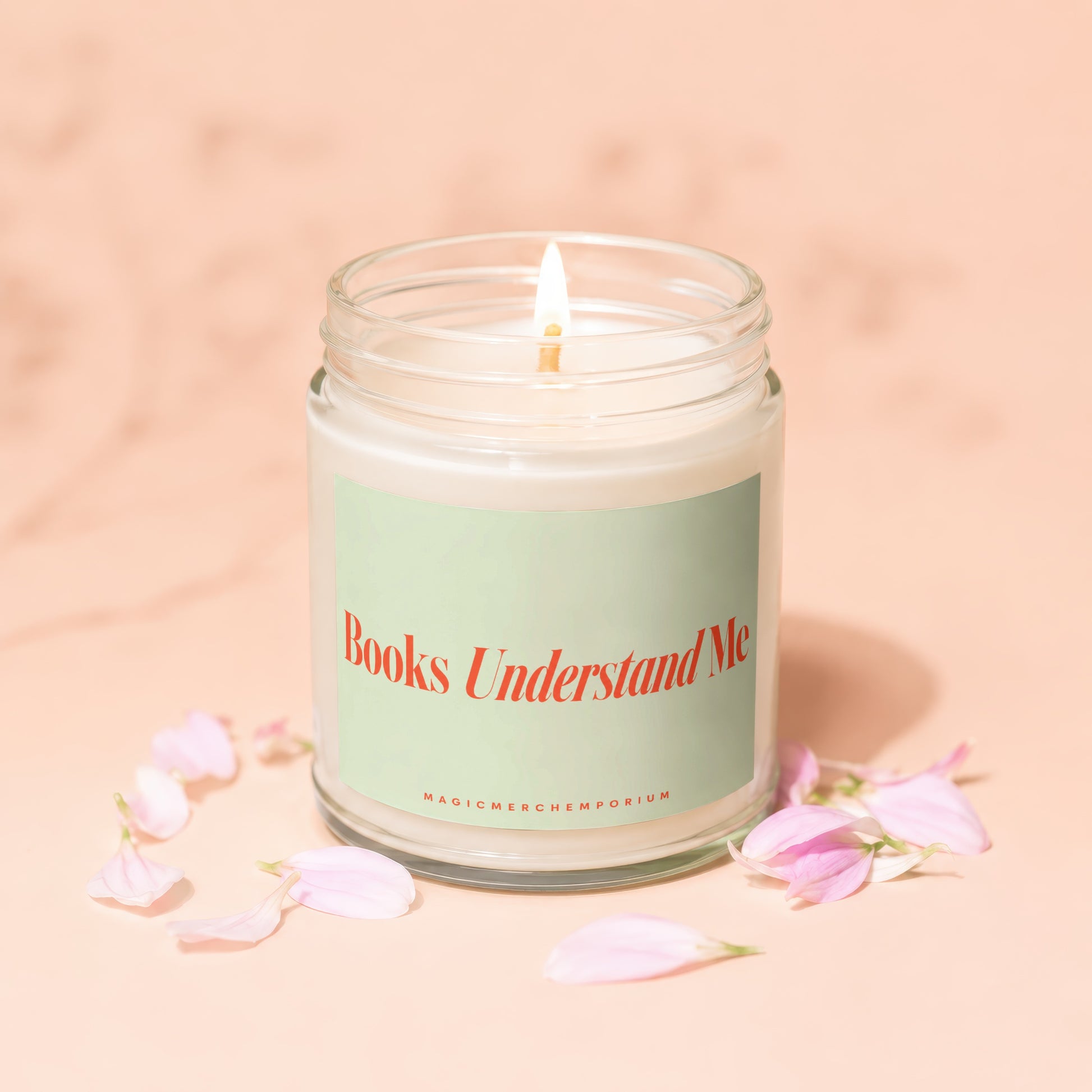 Candle with lit wick on a peach background with pink flower petals.