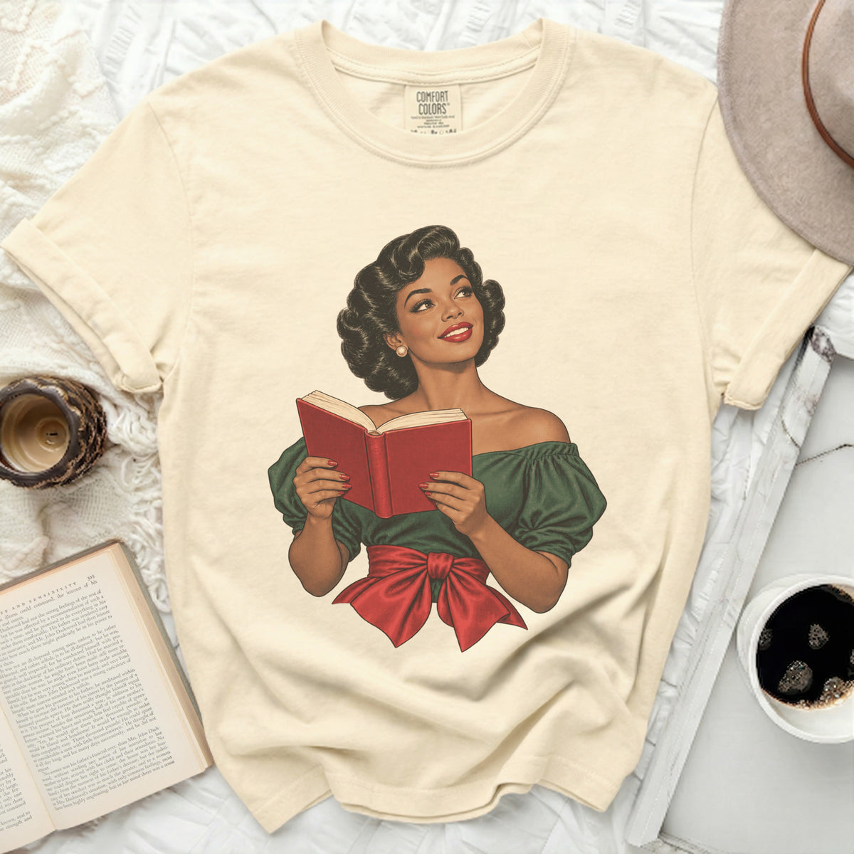 Cream t-shirt with graphic of woman in green dress reading a red book.