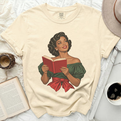 Cream t-shirt with graphic of woman in green dress reading a red book.