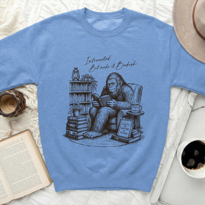 A blue sweatshirt with a Bigfoot reading a book and the text "Introverted. But make it Bookish."