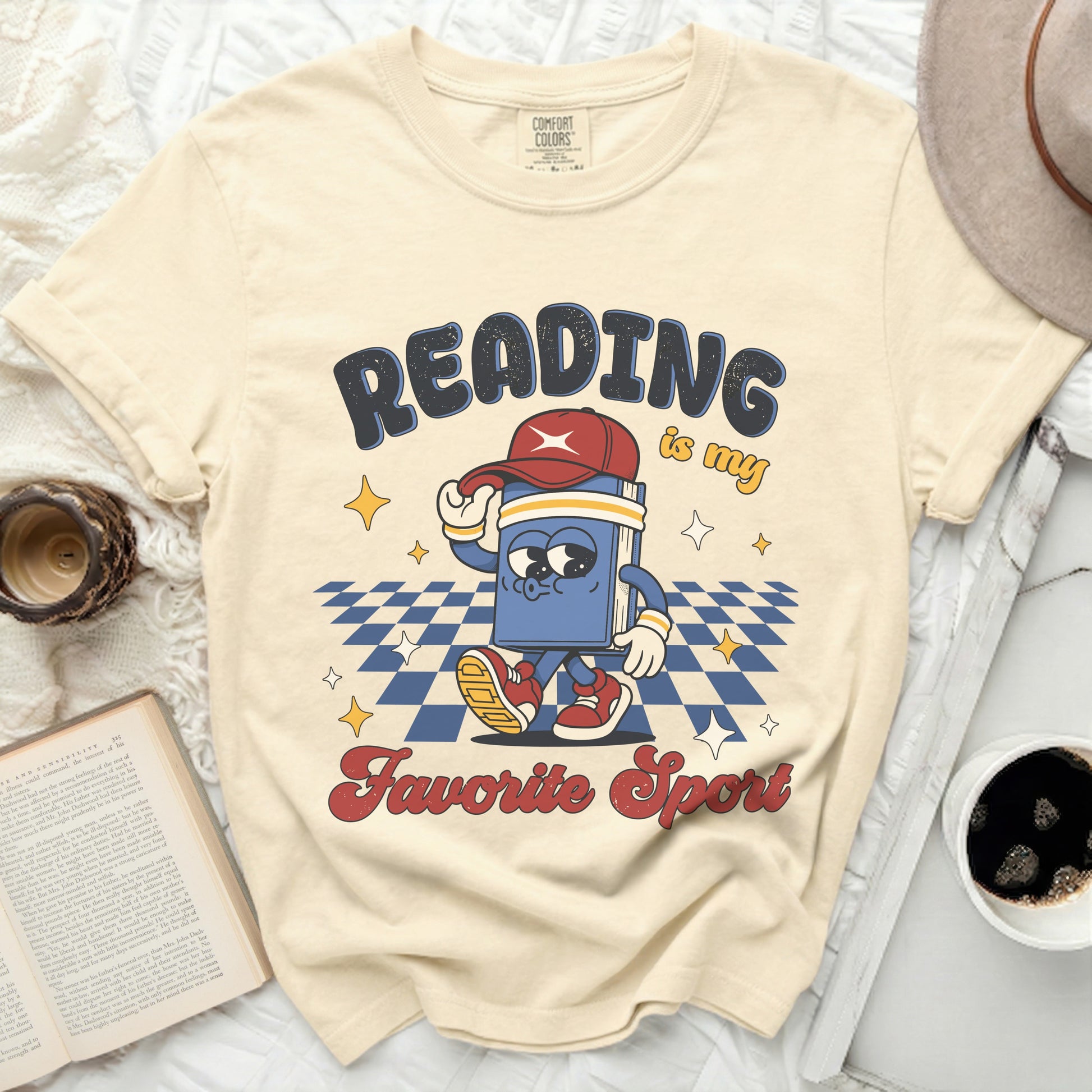 Cream t-shirt with "Reading is my favorite sport" graphic of a walking book.