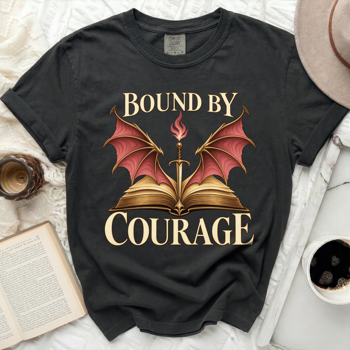 Black t-shirt with "BOUND BY COURAGE" text and a sword above an open book.