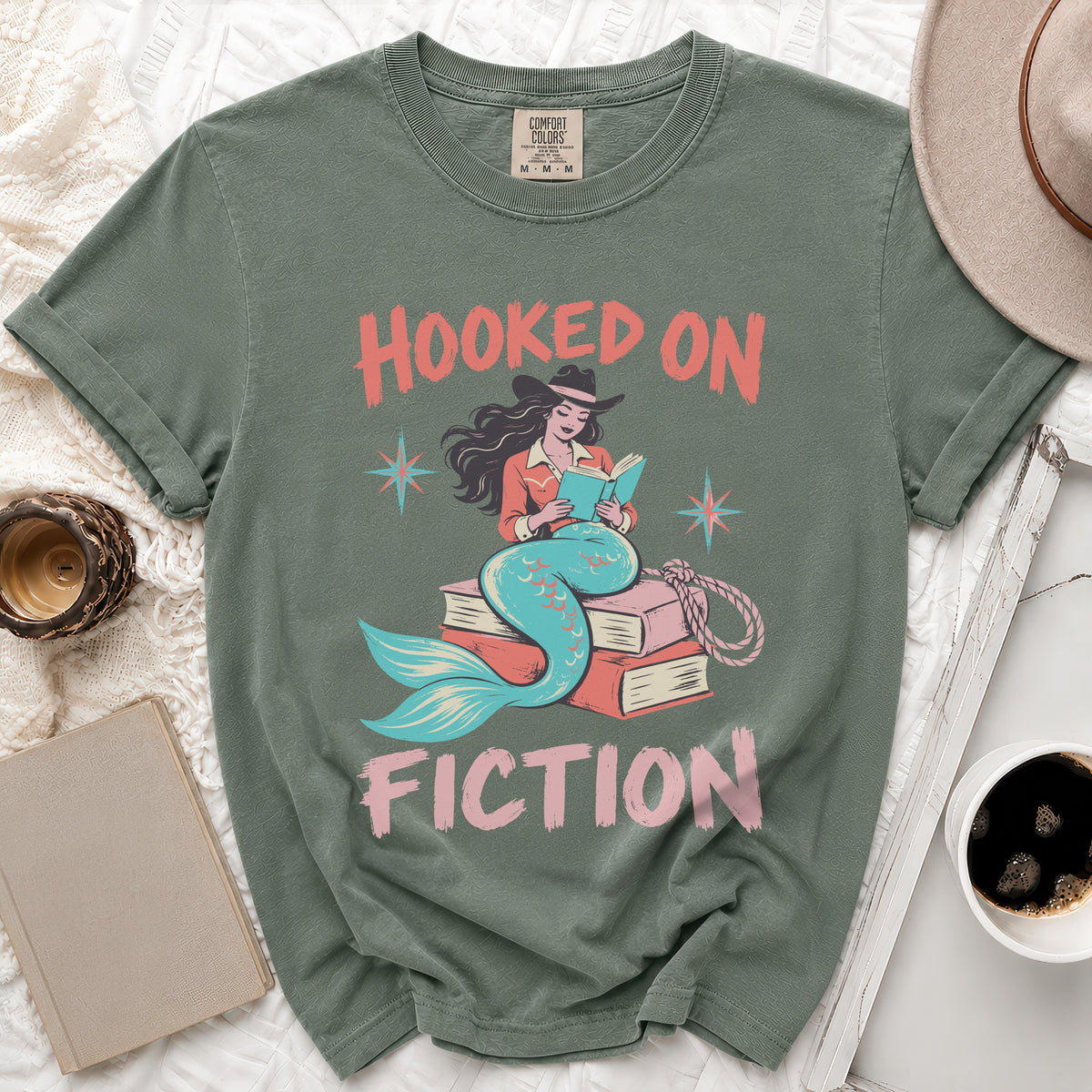 Green t-shirt with "Hooked On Fiction" text and a mermaid reading a book.