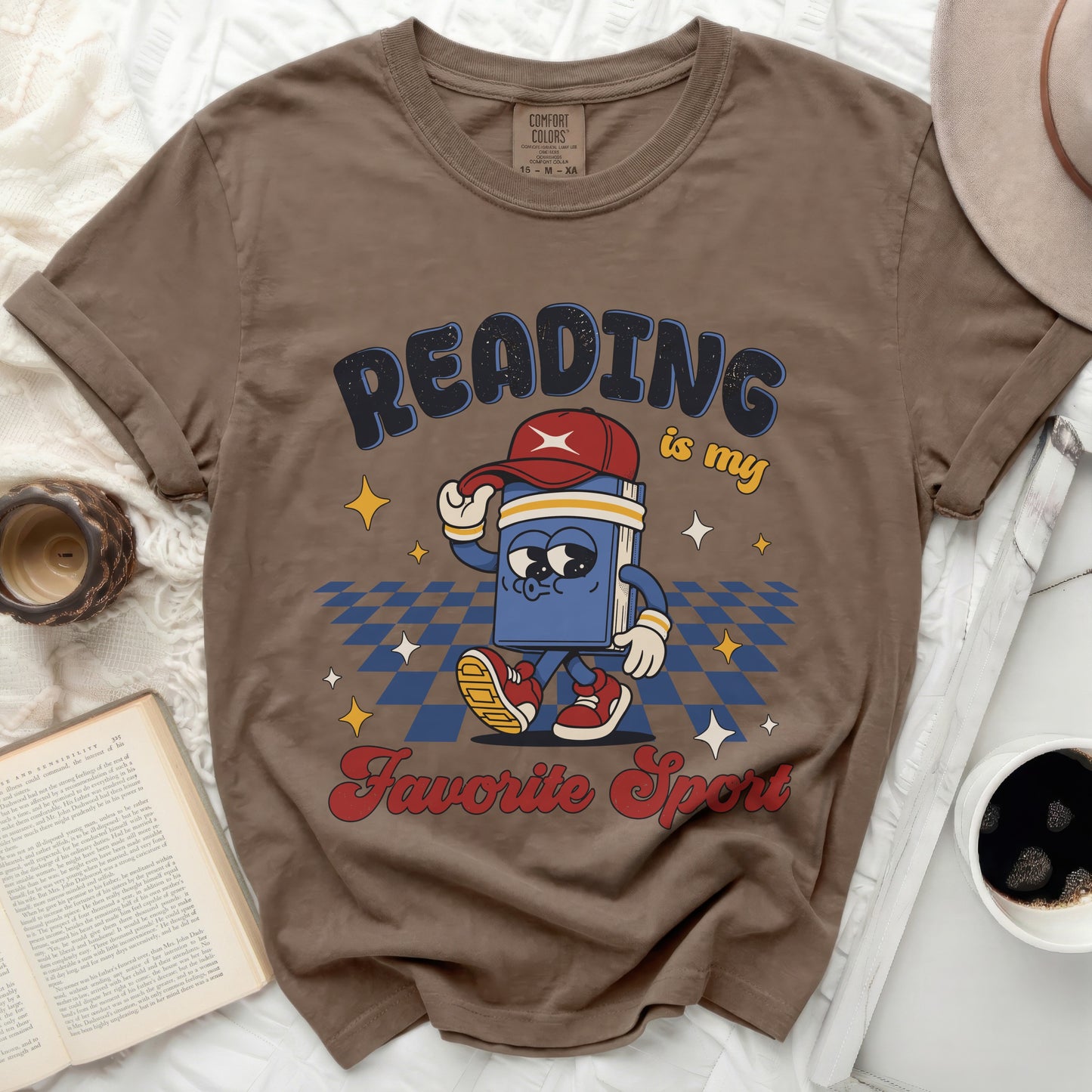 Brown t-shirt with a cartoon book reading "Reading is my favorite sport."