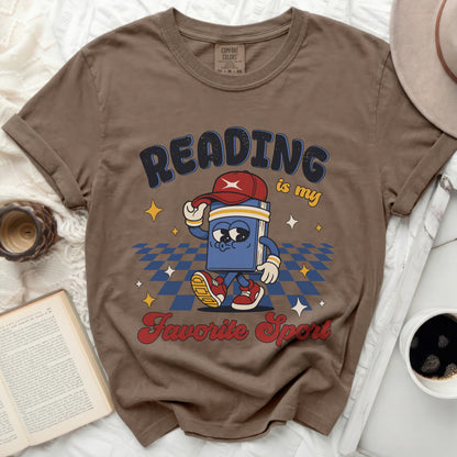 Brown t-shirt with a cartoon book reading "Reading is my favorite sport."