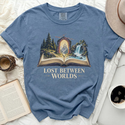 Blue t-shirt with "Lost Between Worlds" text over a fantasy landscape.