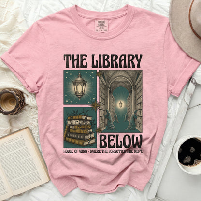 Pink t-shirt with "The Library Below" text and library-themed graphic.