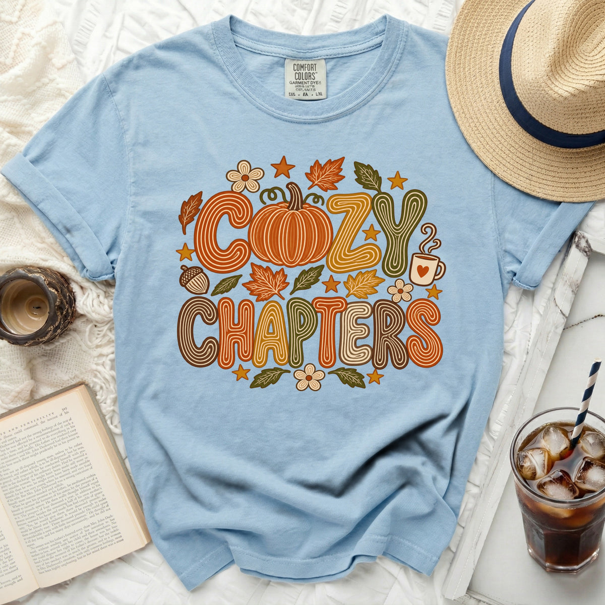 Light blue t-shirt with "Cozy Chapters" and pumpkin graphic.