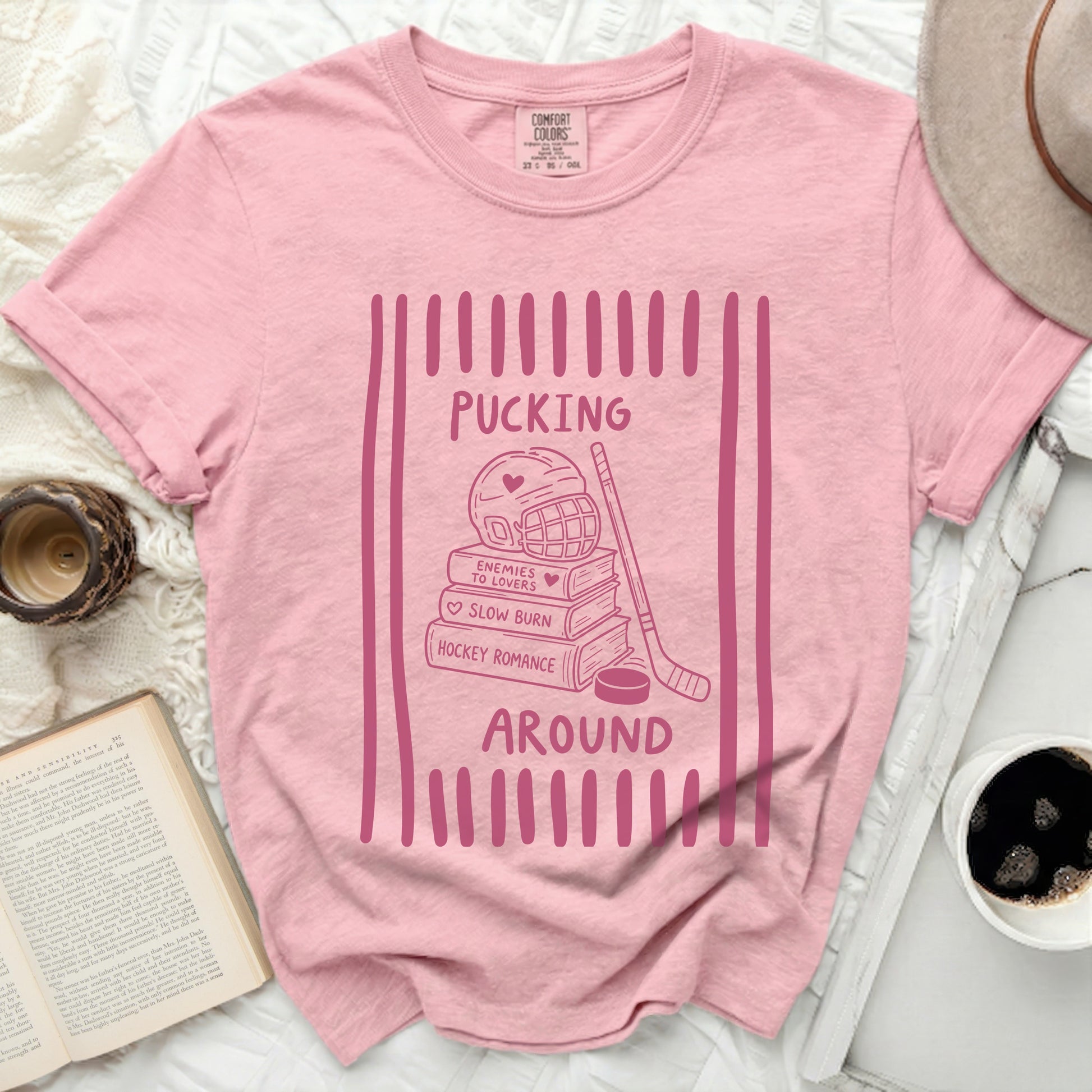 Pink t-shirt with "Pucking Around" hockey romance graphic.