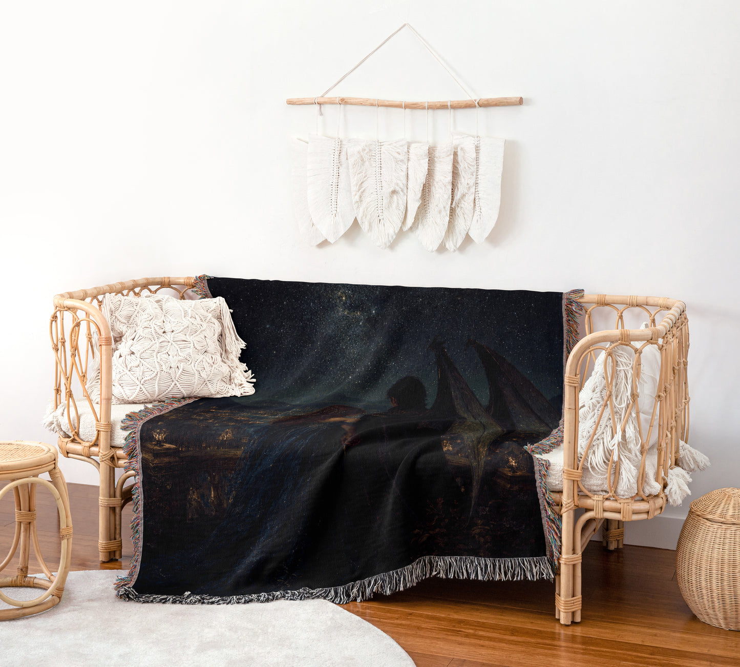 a cozy living room with a wicker sofa adorned with a black and gold throw blanket, a white pillow, and a woven basket. Above the sofa, a hanging white feather decoration adds a touch of whimsy to the space.