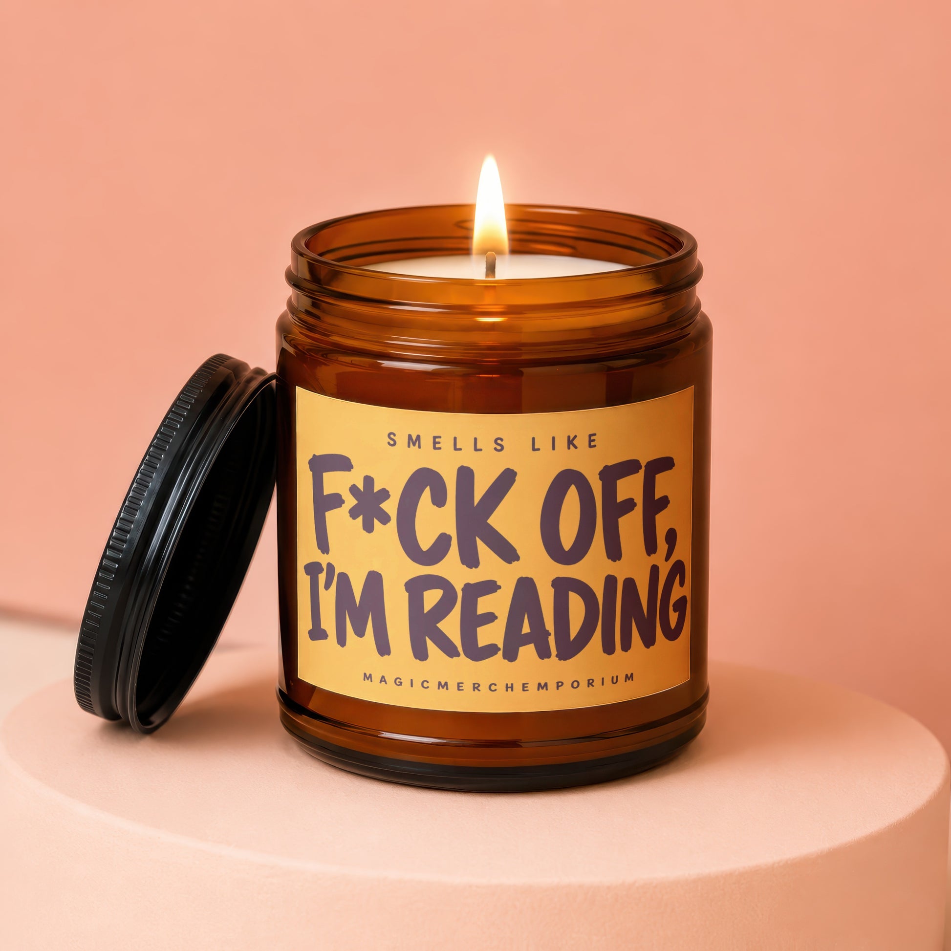 Amber jar candle with lit flame and label reading "F*ck off, I'm reading."