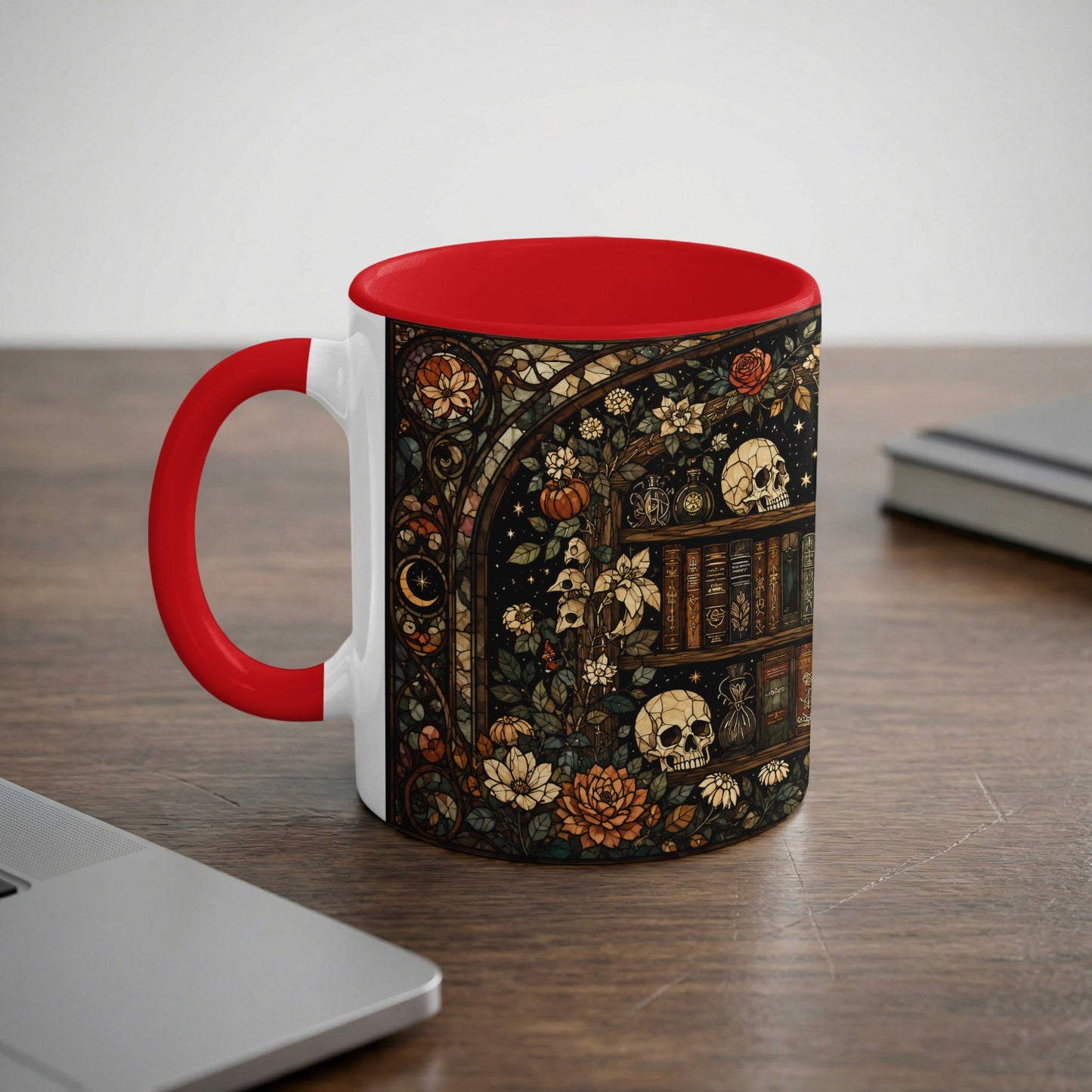 White mug with red accent featuring stained glass art of skulls, books, and flowers.