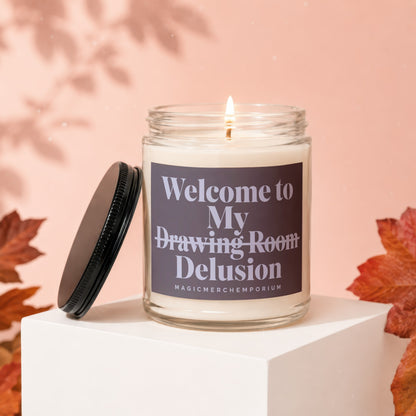 Candle with label "Welcome to My Drawing Room Delusion" on white block.