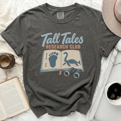 Dark grey t-shirt with "Tall Tales Research Club" and open book graphic.