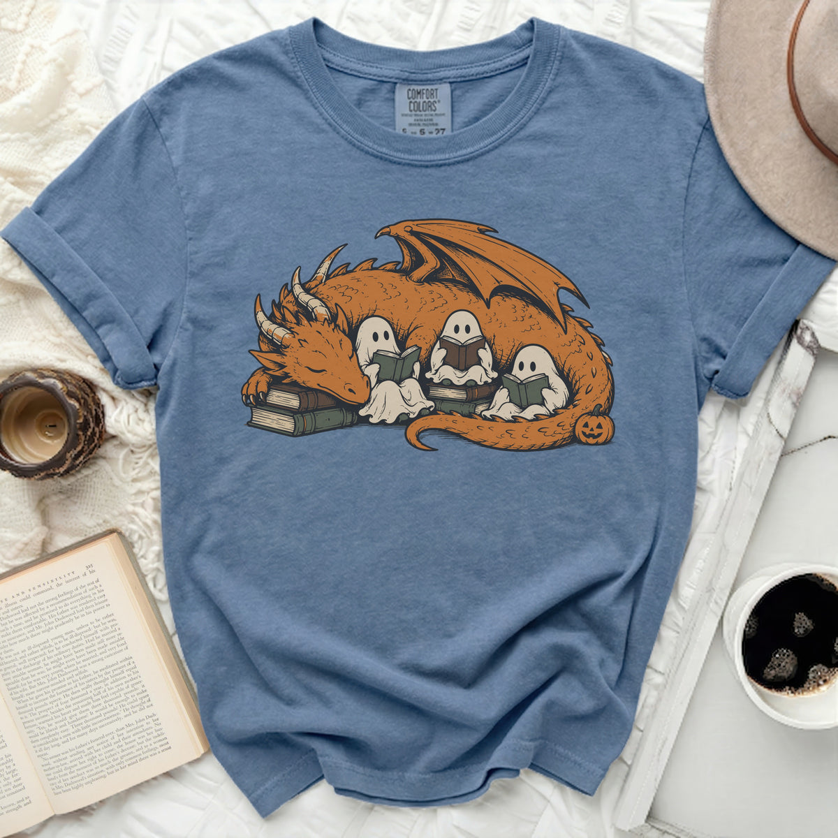 Blue t-shirt with graphic of orange dragon sleeping on books with three ghosts reading.