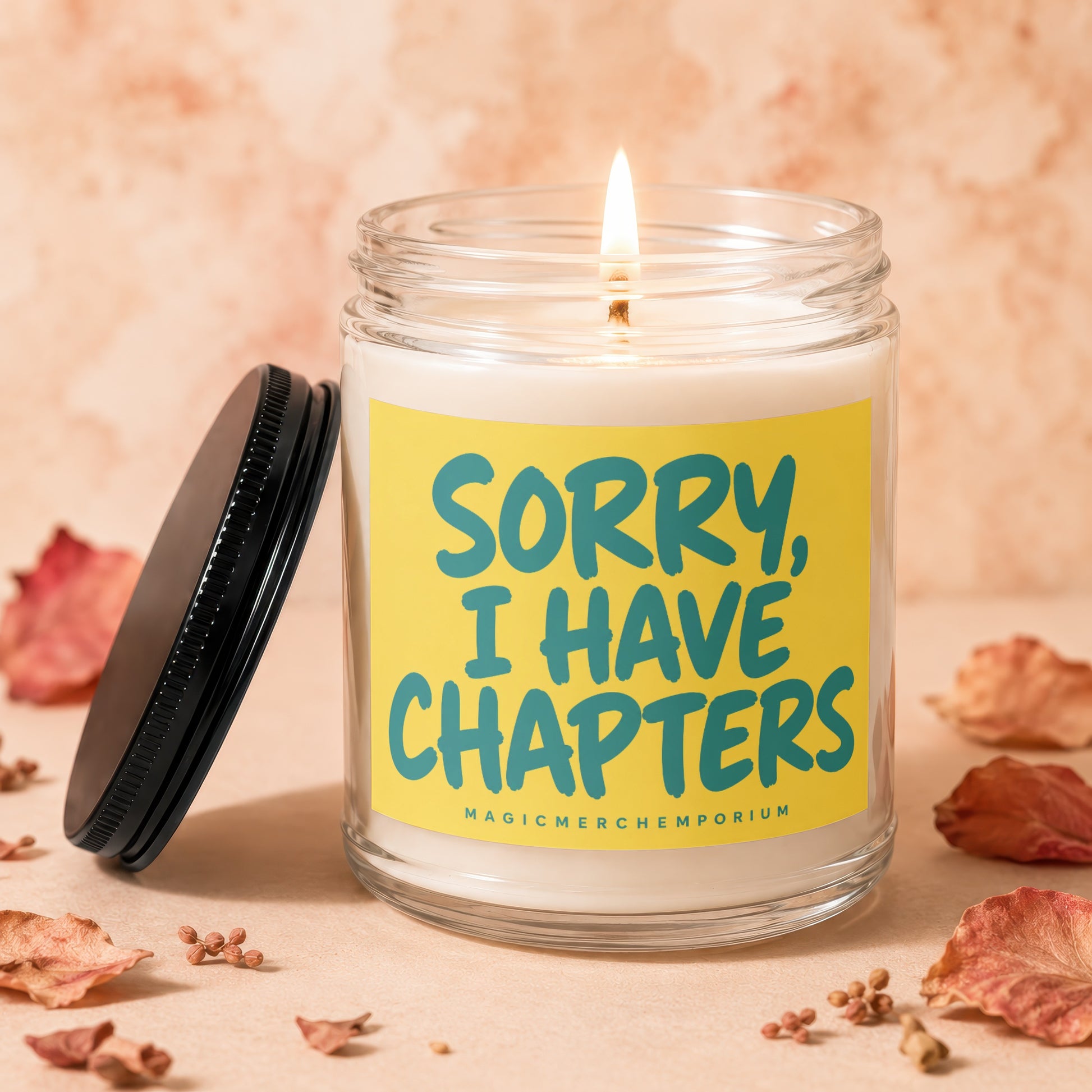 Lit jar candle with yellow label and teal text reading "SORRY, I HAVE CHAPTERS".
