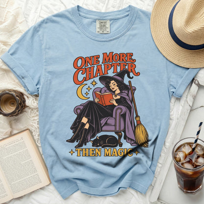 Light blue t-shirt with graphic of witch reading, cat, and text "One More Chapter Then Magic."