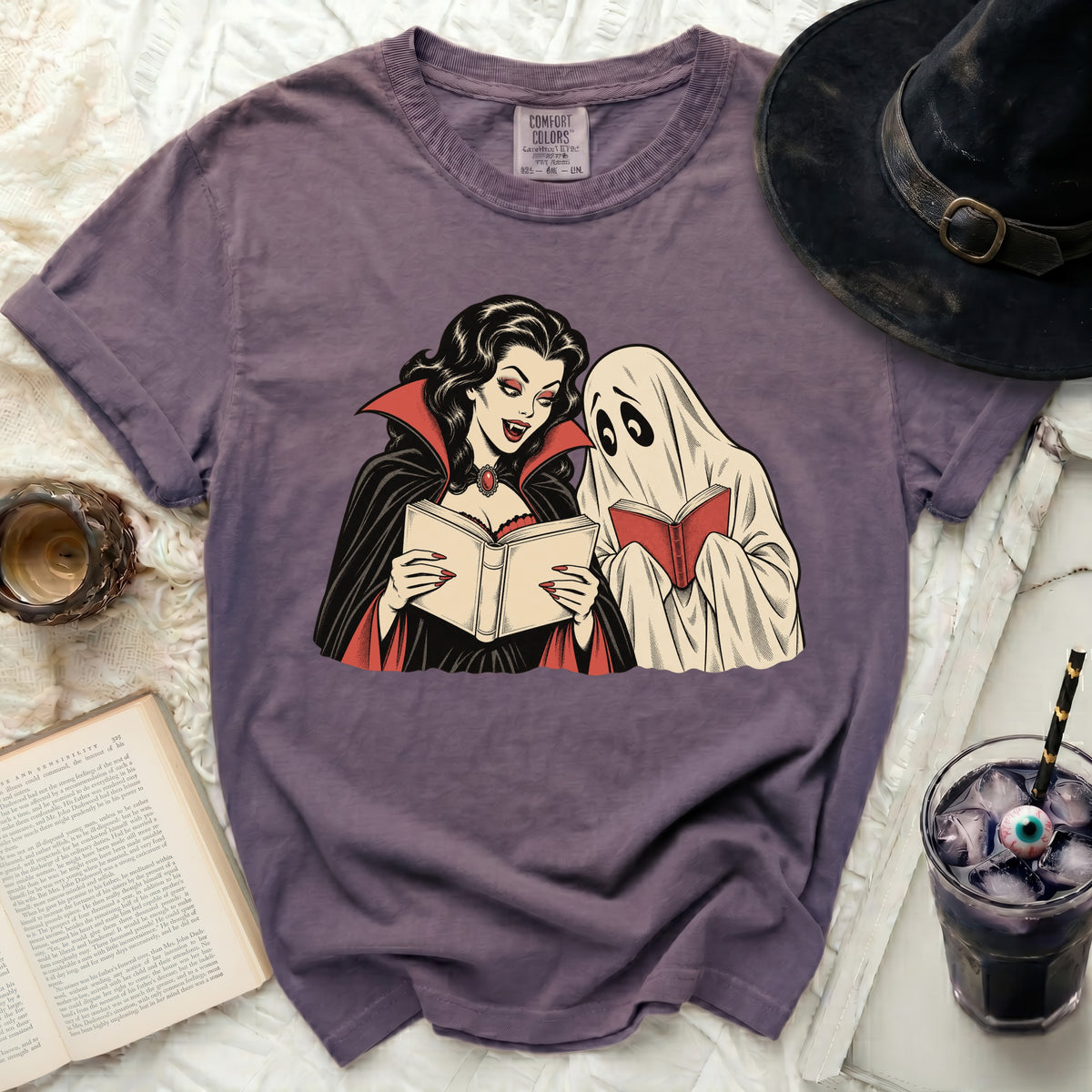 Purple t-shirt with vampire and ghost reading books graphic.