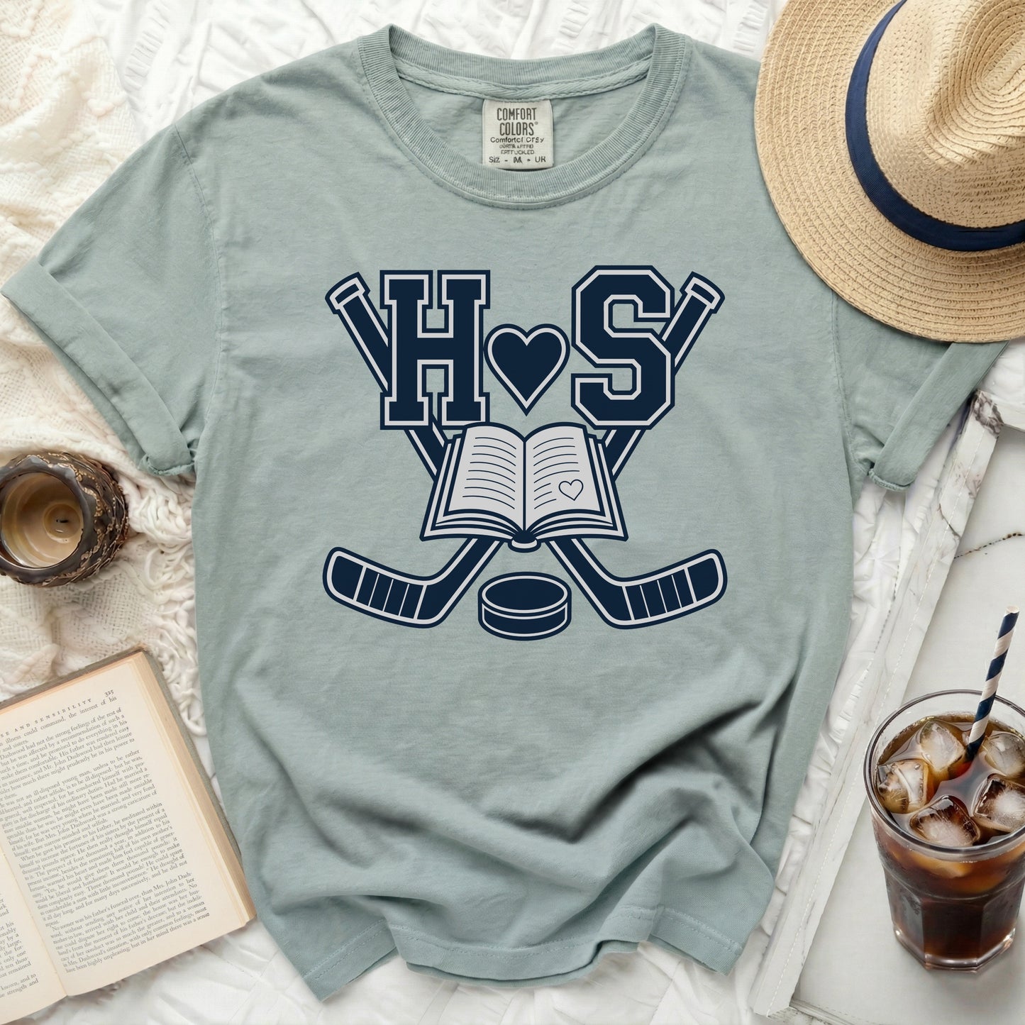 Green t-shirt with hockey sticks, book, and "HS" logo.