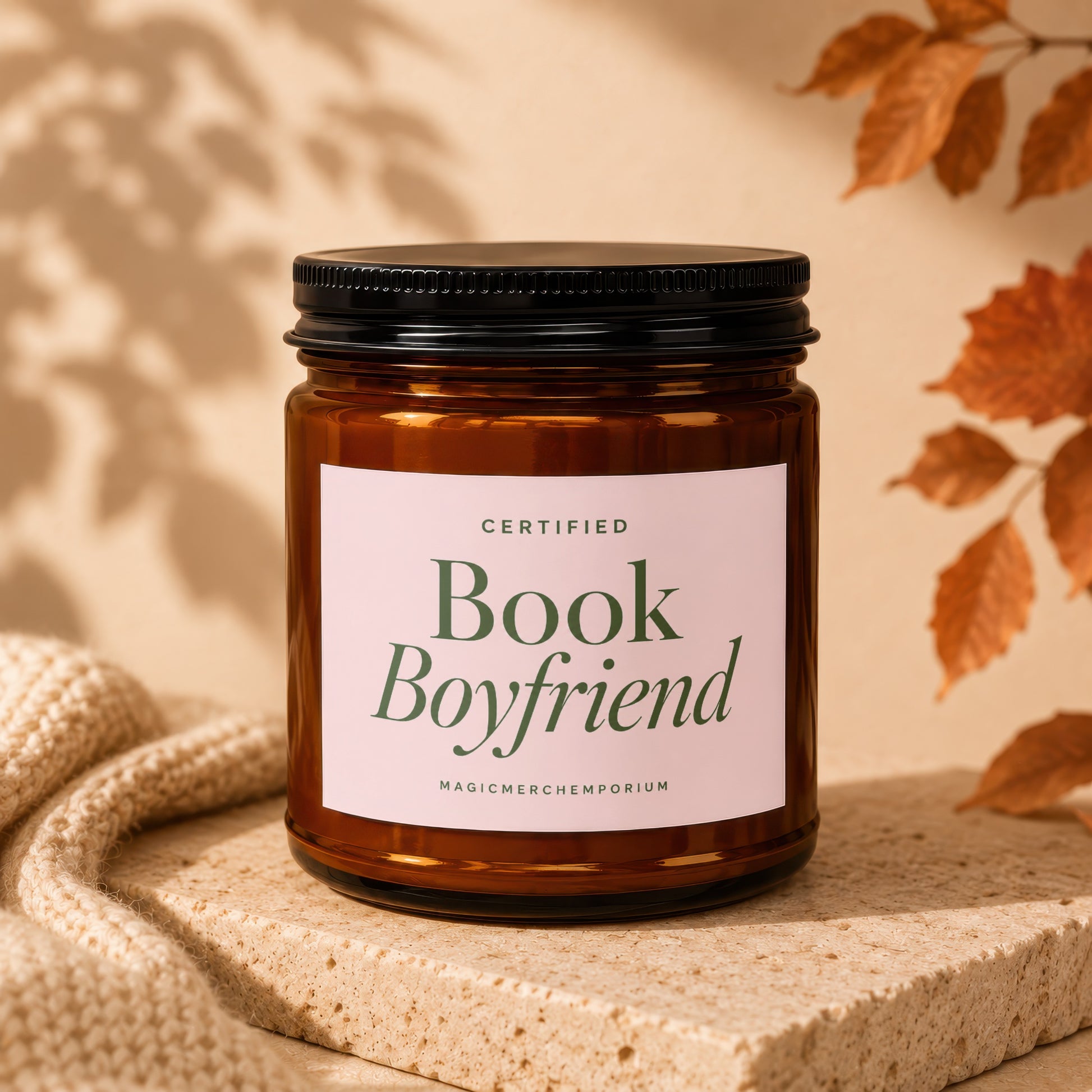 Amber jar candle with "Certified Book Boyfriend" label on textured stone.