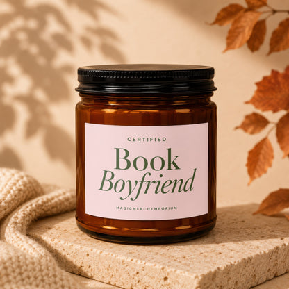 Amber jar candle with "Certified Book Boyfriend" label on textured stone.