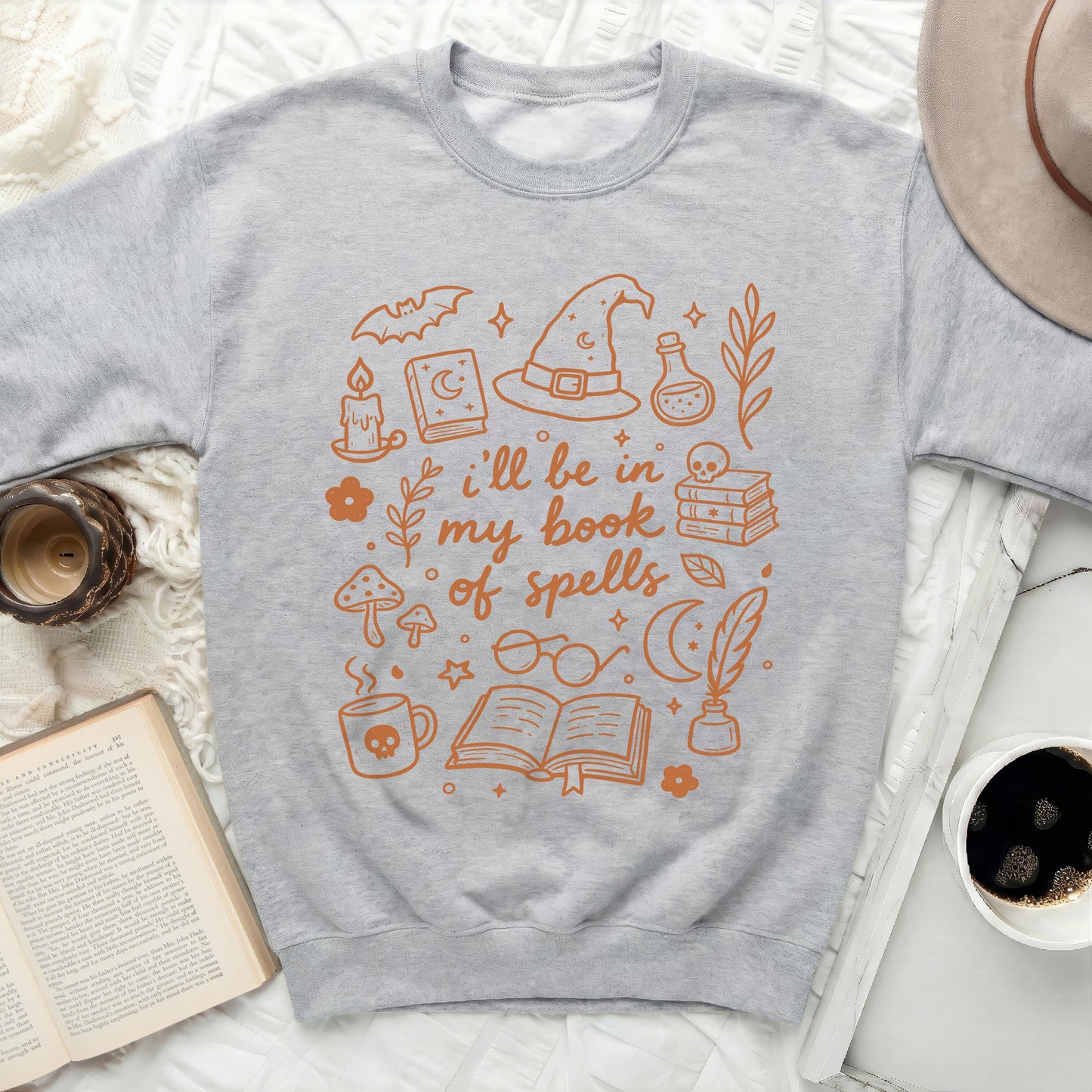 Sweatshirt with orange outline drawings of witchy items and the text "i'll be in my book of spells".