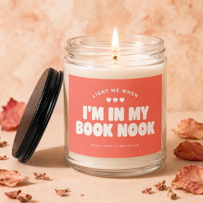 Glass candle with "Light me when I'm in my book nook" text and black lid.