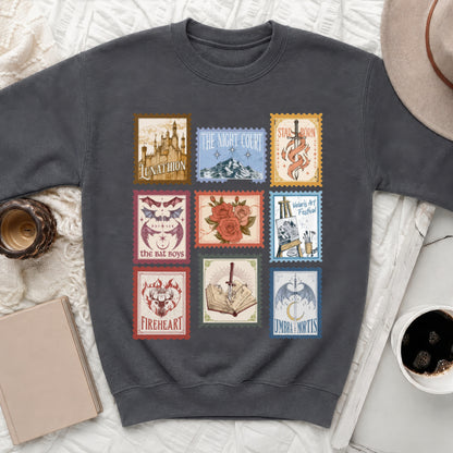 Dark grey sweatshirt with nine postage stamp designs, featuring castles, mountains, swords, and dragons.