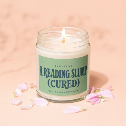 Lit candle in a glass jar with green label reading "Smells Like A Reading Slump (Cured)".