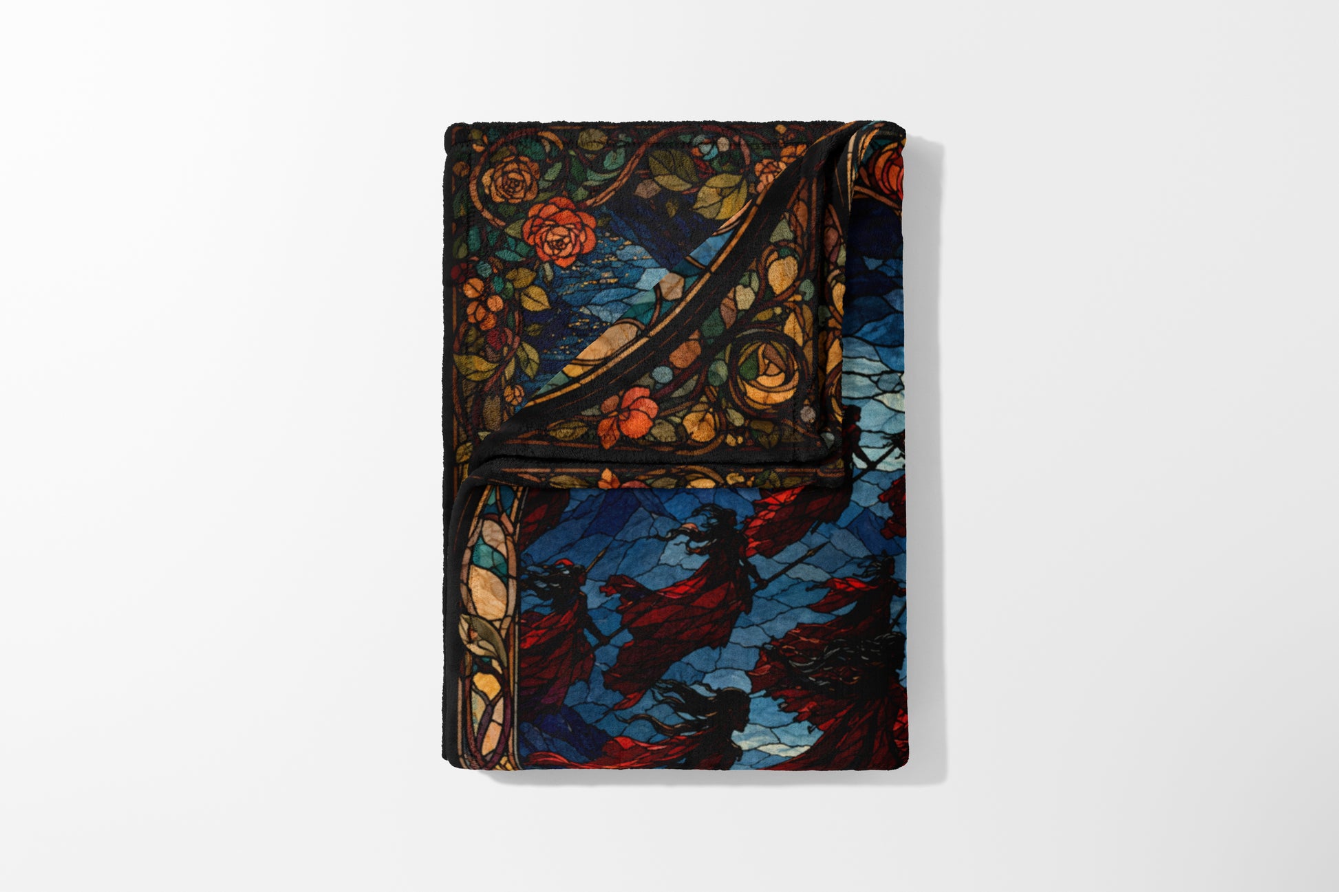 Folded blanket with stained glass design of roses and figures in red cloaks.