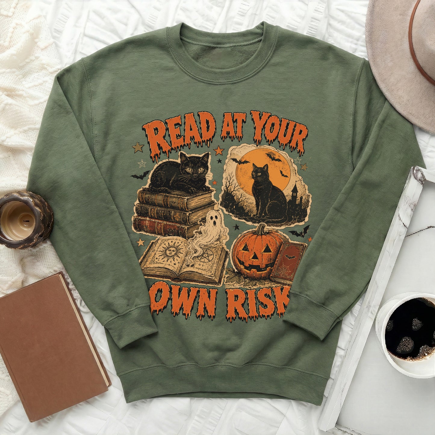 Green sweatshirt with "Read at Your Own Risk" Halloween graphic featuring cats, books, and a pumpkin.