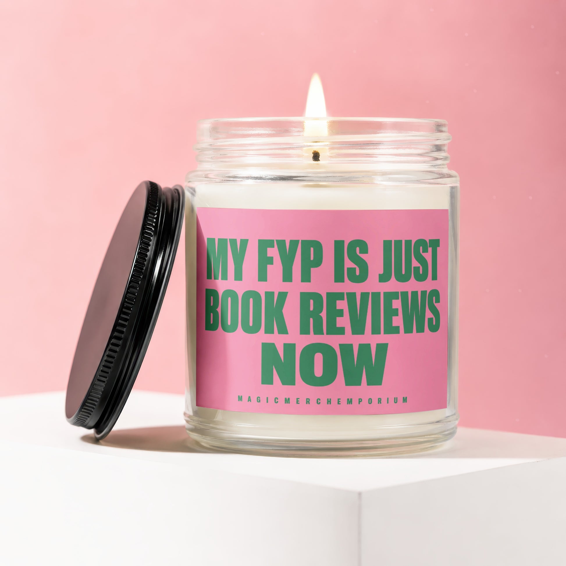 Glass candle with lit wick and pink label reading "MY FYP IS JUST BOOK REVIEWS NOW".