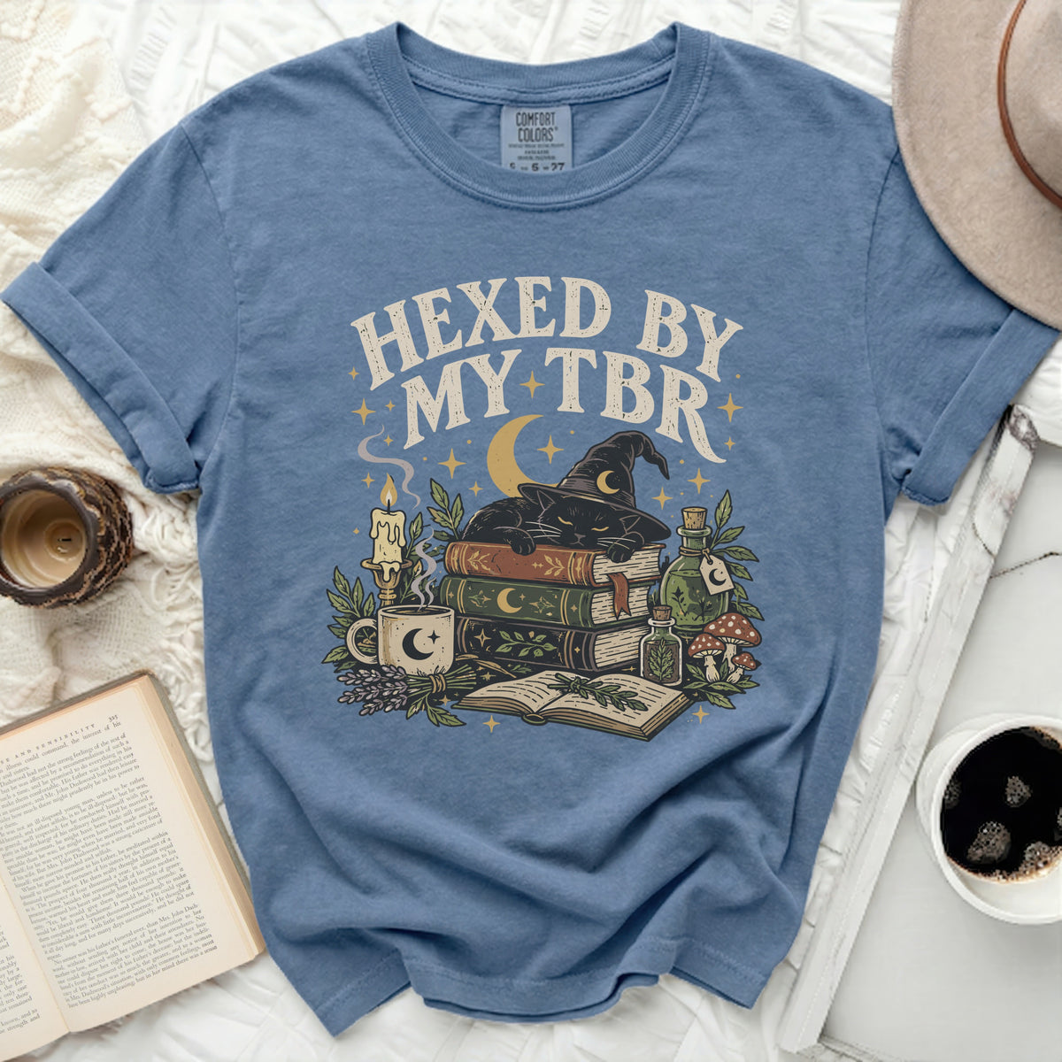 Blue t-shirt with "Hexed By My TBR" text, black cat, books, and potion bottles.