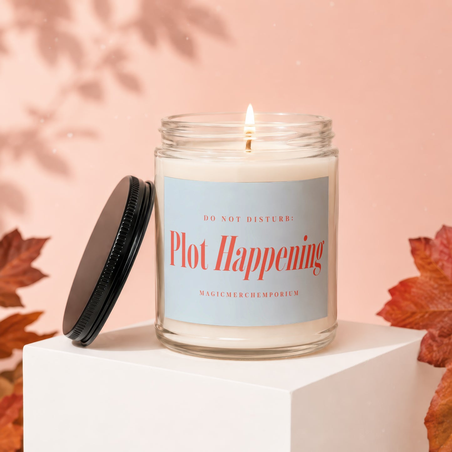 Scented candle with "DO NOT DISTURB: Plot Happening" text on label.