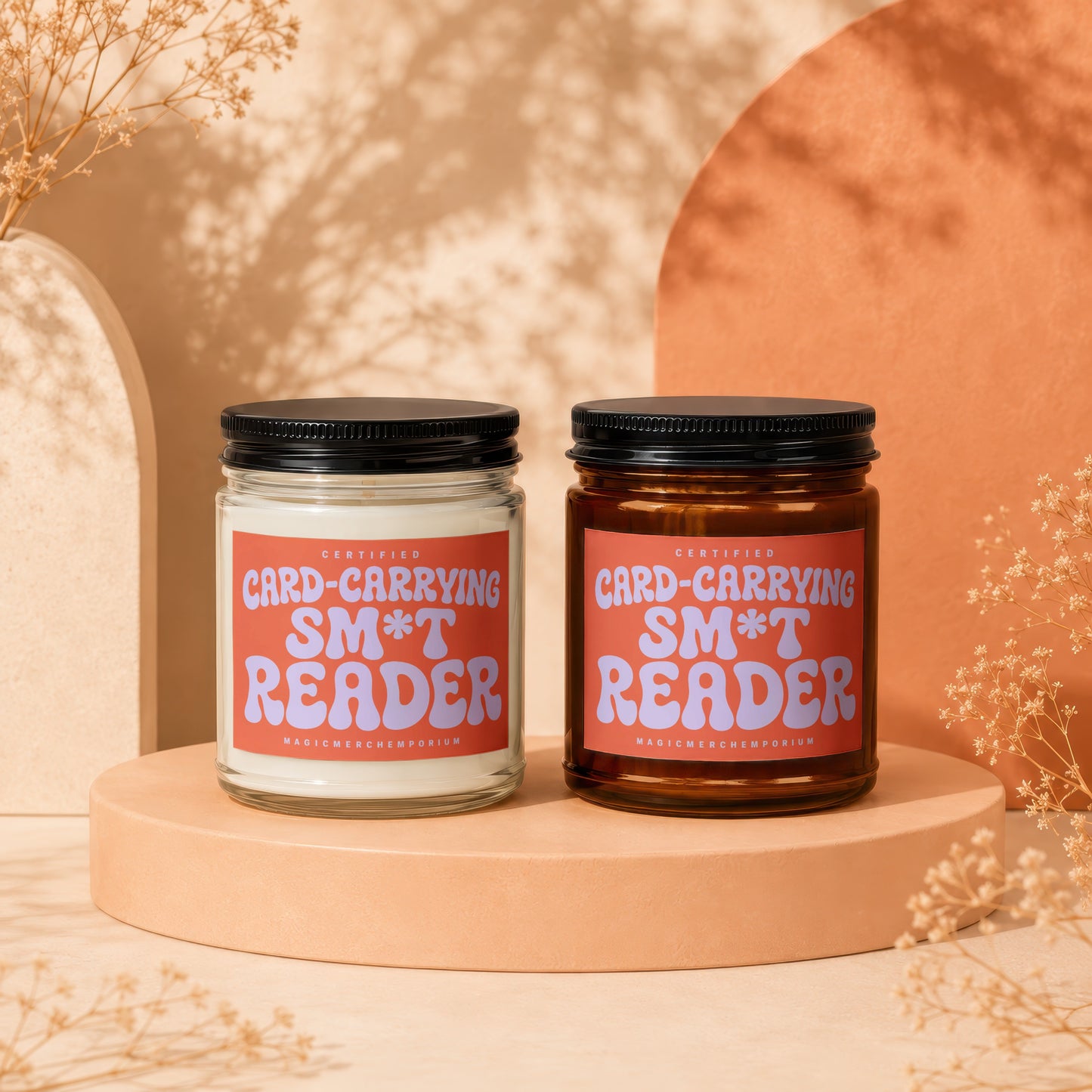 Two candles on display pedestals with labels reading "Certified Card-Carrying Sm*t Reader".