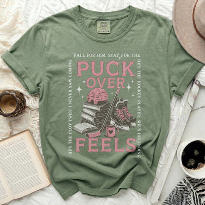 Green t-shirt with hockey and book graphics and text about "puck over feels".