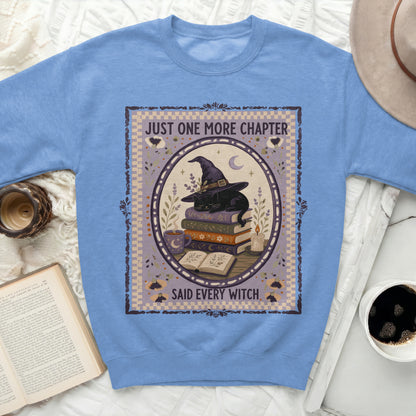 Blue sweatshirt with a graphic of a black cat in a witch hat reading a book.