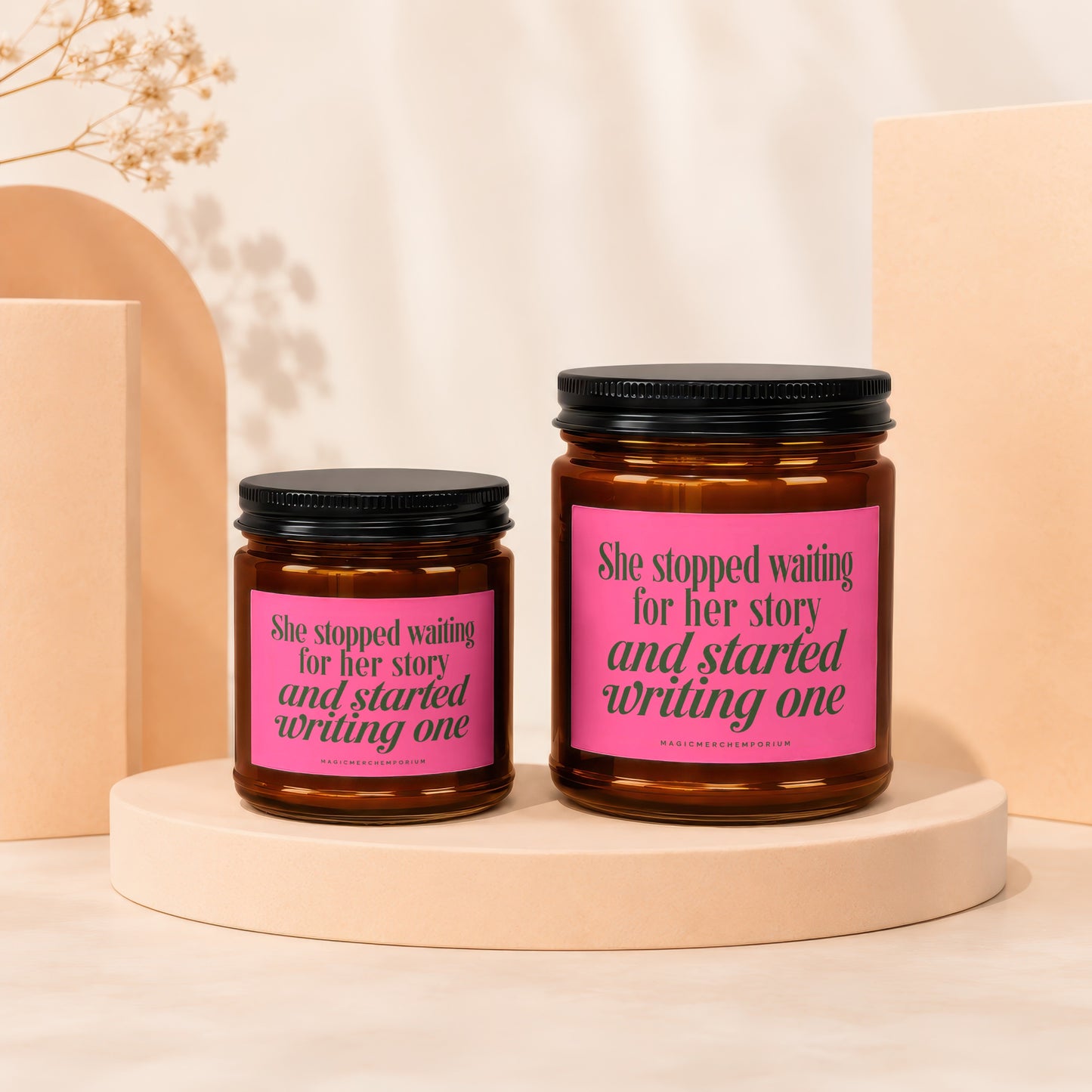 Two amber jars with black lids, pink labels reading "She stopped waiting for her story and started writing one".
