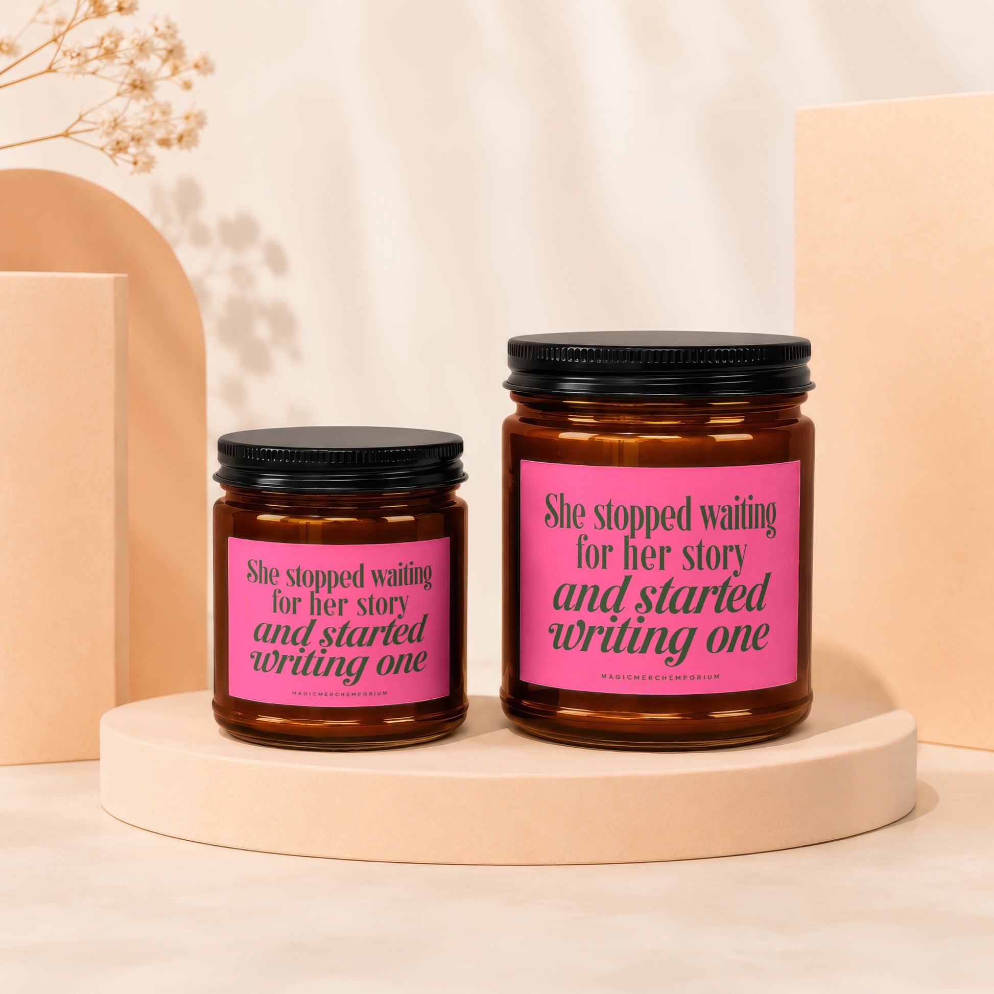 Two amber jars with black lids, pink labels reading "She stopped waiting for her story and started writing one".