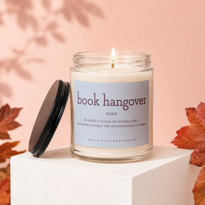 Lit candle in glass jar with "book hangover" definition label, lid off.