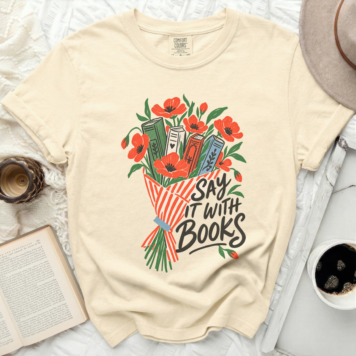 Cream t-shirt with "Say It With Books" design and floral book illustration.