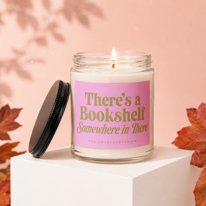 Scented candle with pink label reading "There's a Bookshelf Somewhere in There".