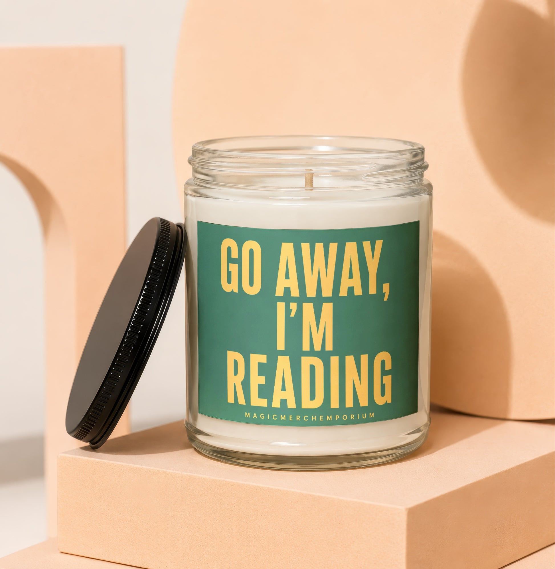 Glass jar candle with green label reading "GO AWAY, I'M READING".