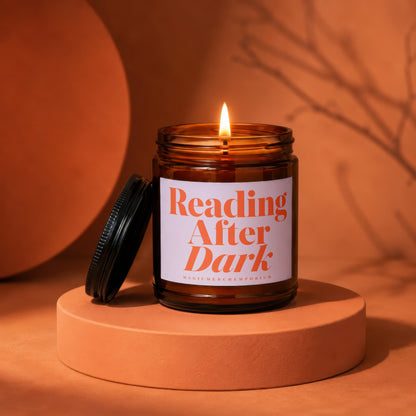 Amber glass candle lit with black lid, labeled "Reading After Dark".