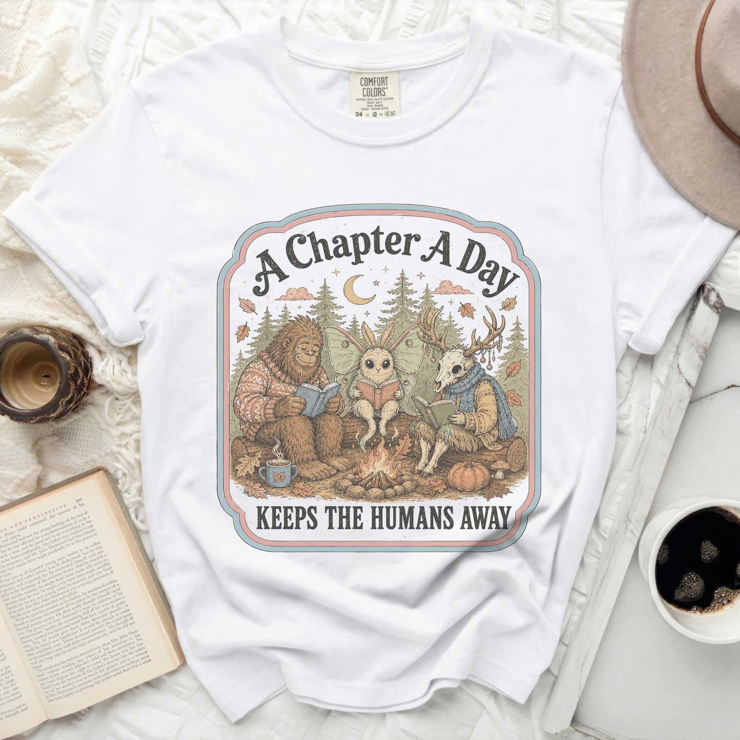 Bigfoot, moth, and deer read books by a campfire, "A Chapter A Day Keeps The Humans Away."