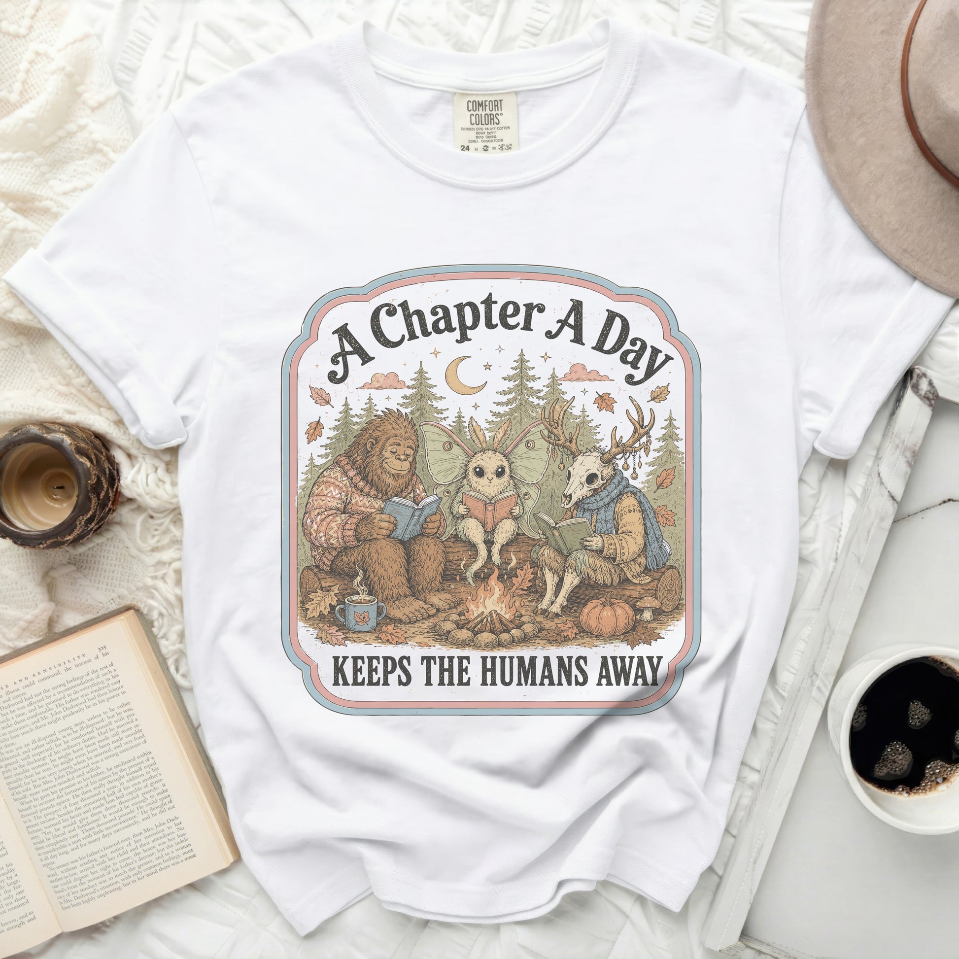 Bigfoot, moth, and deer read books by a campfire, "A Chapter A Day Keeps The Humans Away."