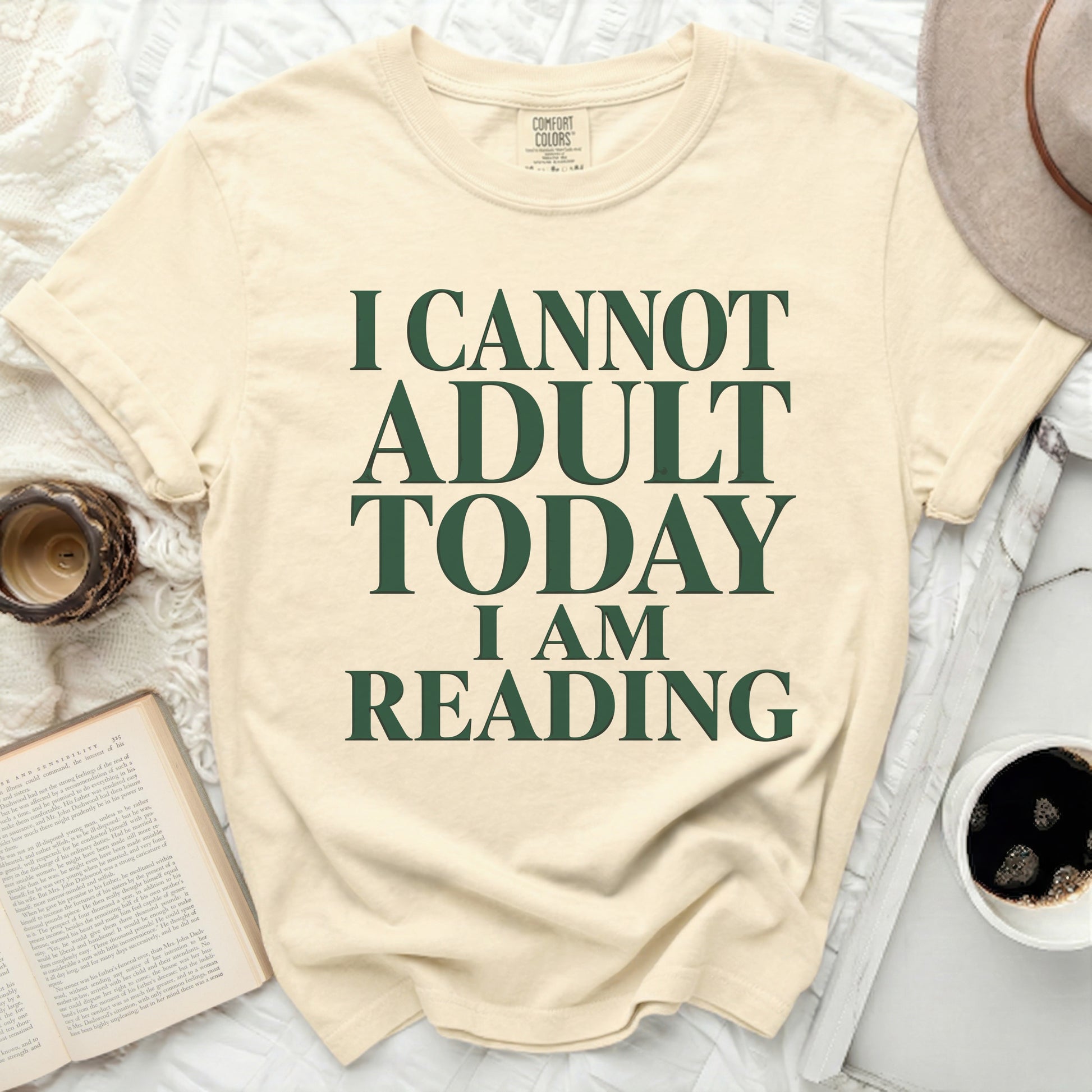 Cream t-shirt with green text "I CANNOT ADULT TODAY I AM READING."