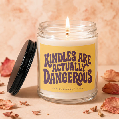 Glass candle with lit wick and yellow label reading "KINDLES ARE ACTUALLY DANGEROUS".