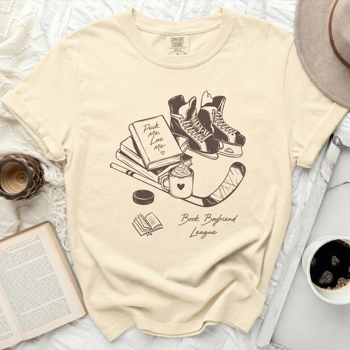 Cream t-shirt with hockey skates, book, and text "Puck Me Love Me" and "Book Boyfriend League".