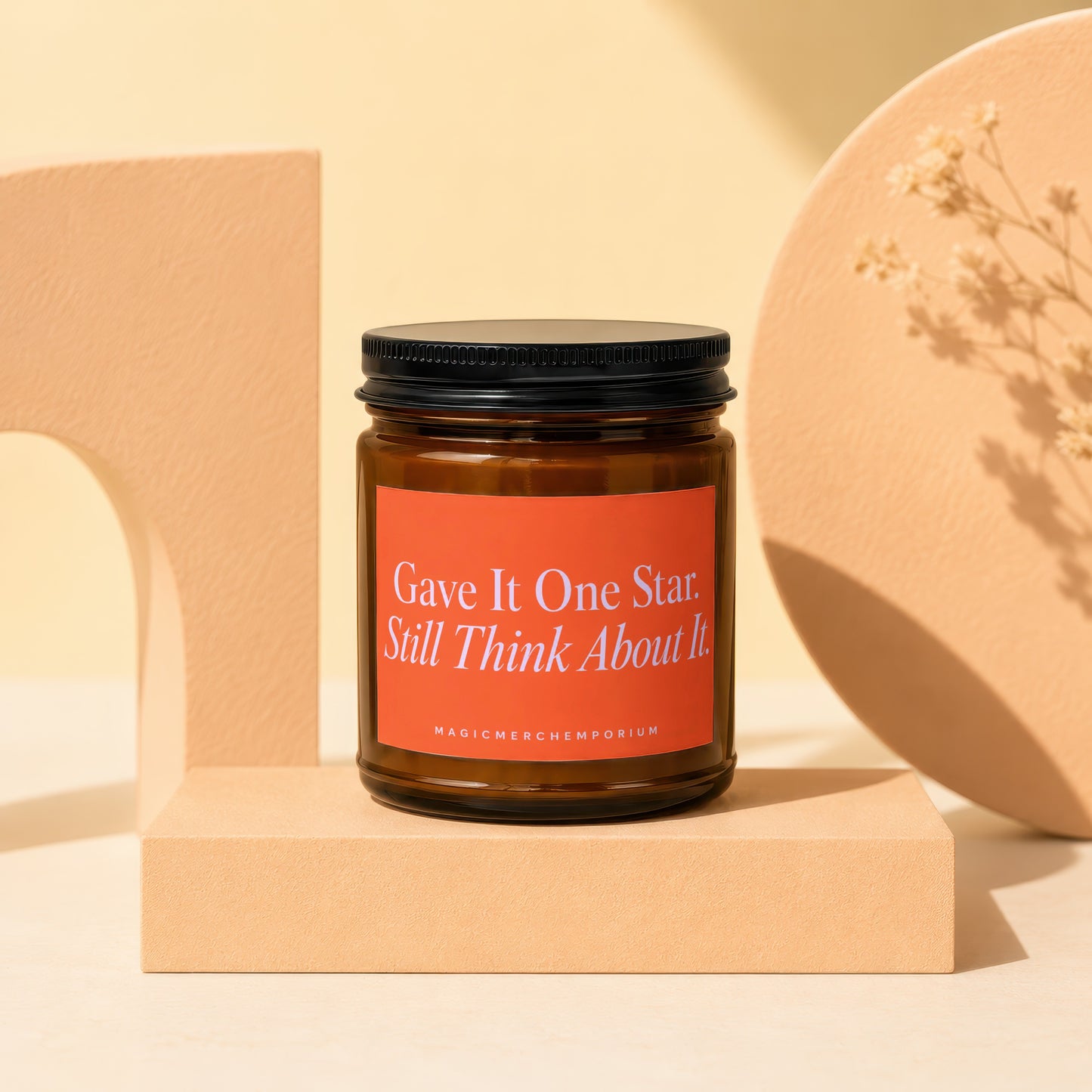 Amber jar candle with black lid and an orange label reading "Gave It One Star. Still Think About It."